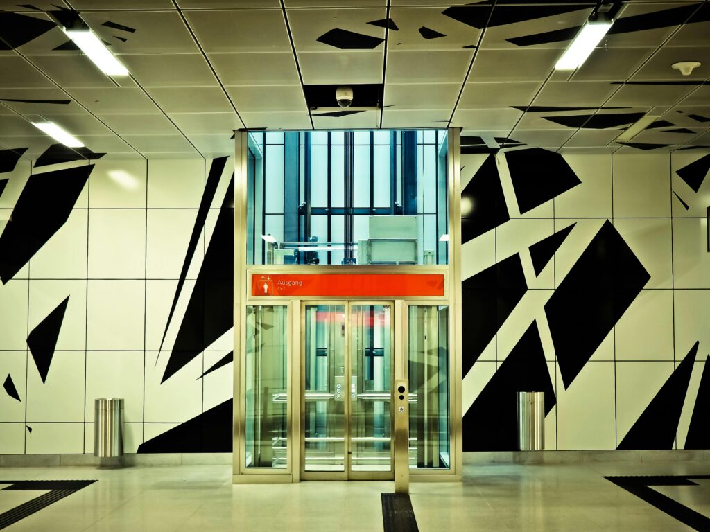 A vibrant modern subway station entrance with geometric patterns and glass elevators.